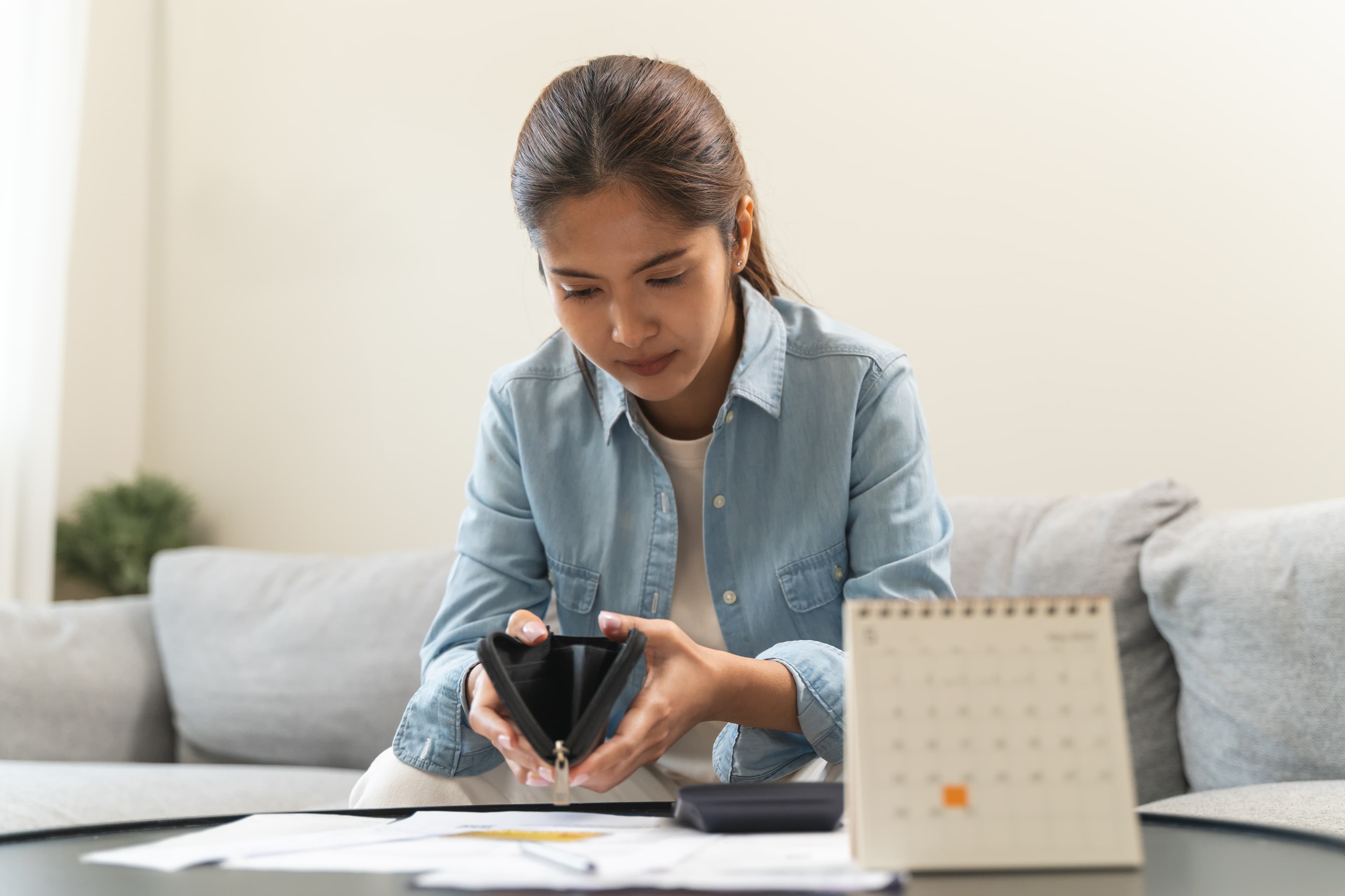 person-checking-wallet-with-few-bills-before-payday-while-looking-at-calendar