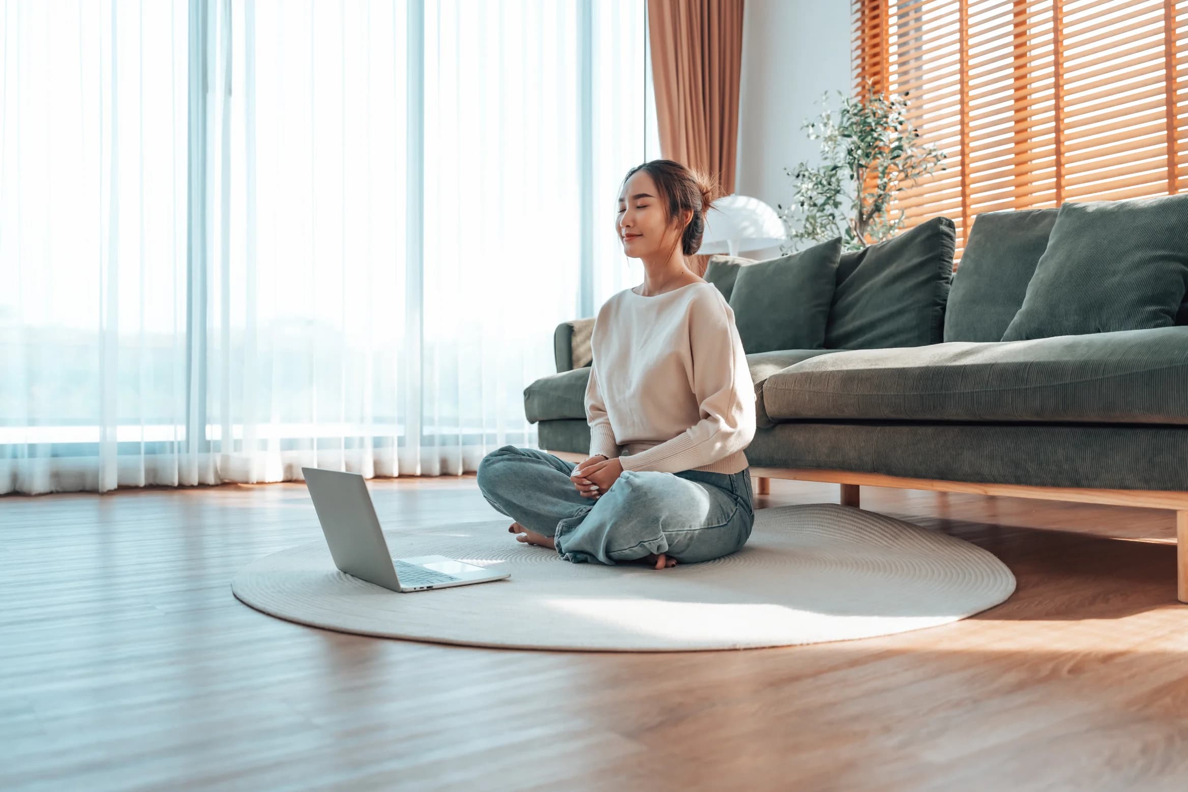Happy young Asian woman practicing meditation at home with laptop