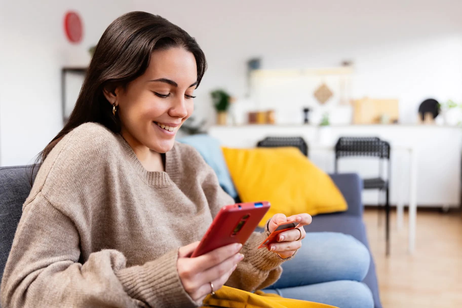 woman-making-secure-digital-payment-on-smartphone-while-holding-credit-card-at-home